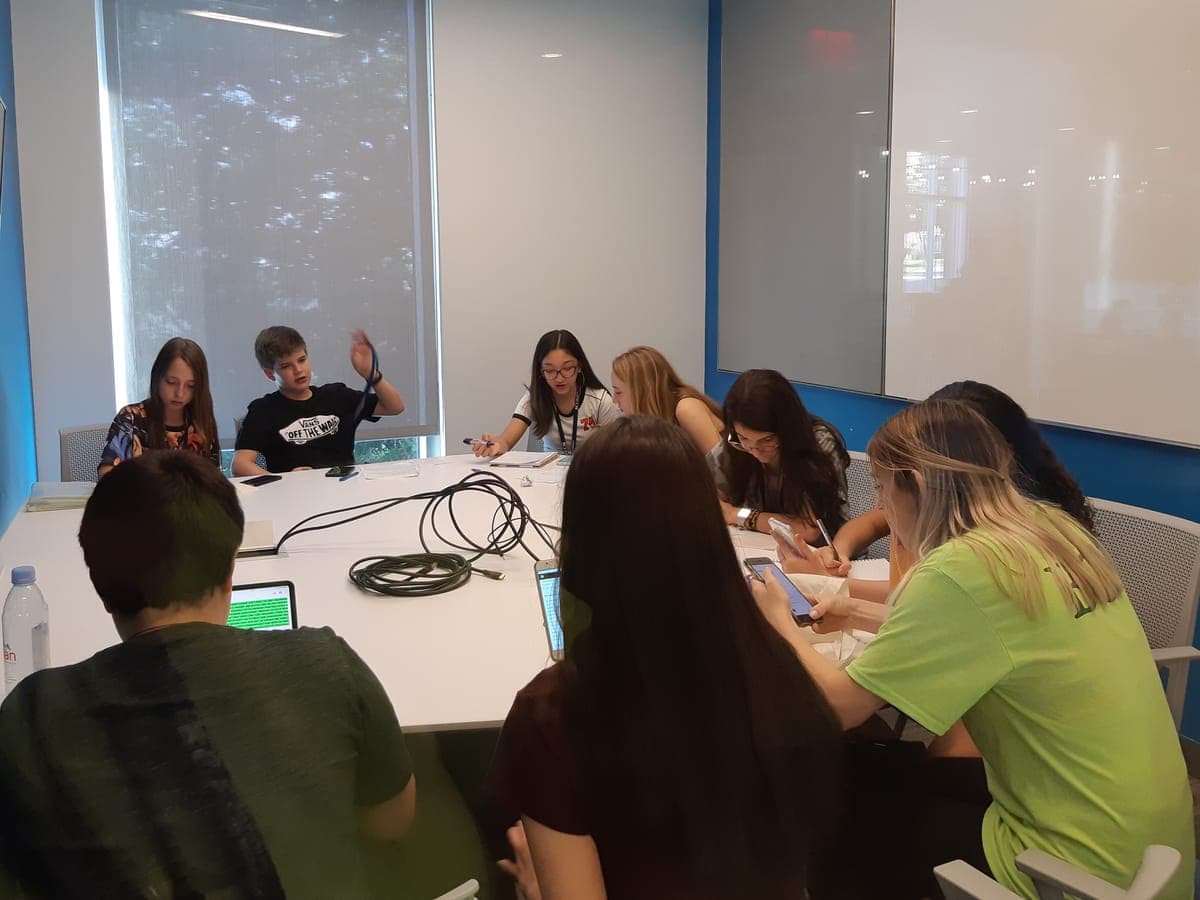 Team around the meeting table with laptops and worksheets, developing their project with a BCI monitor in the group.