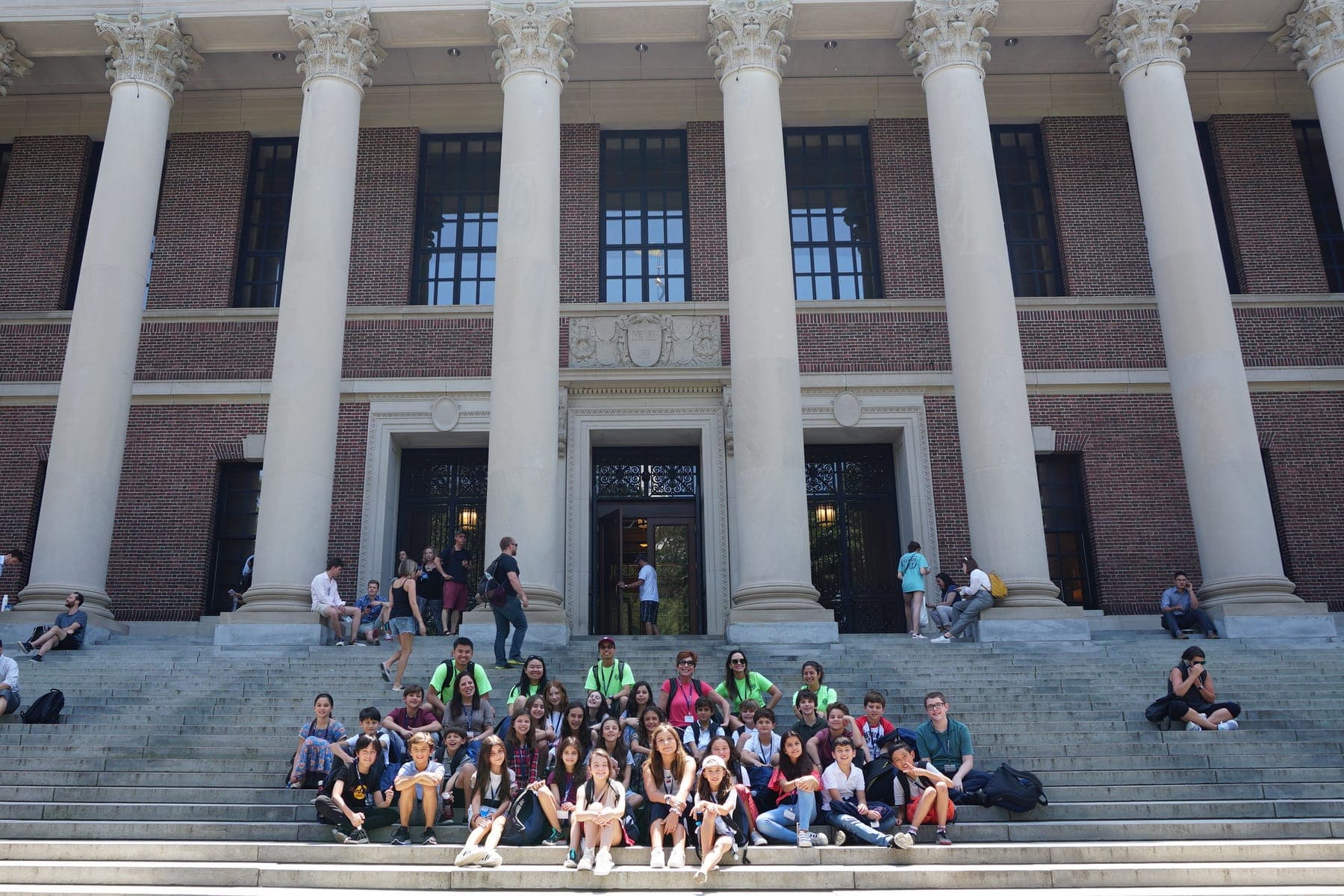 A BCI group seated on the stone steps of a monumental building, between the columns of its facade.