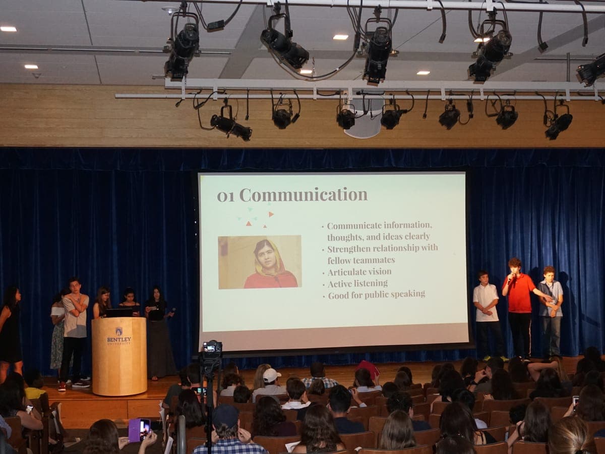 Final presentation by a team on stage, project slide behind them.