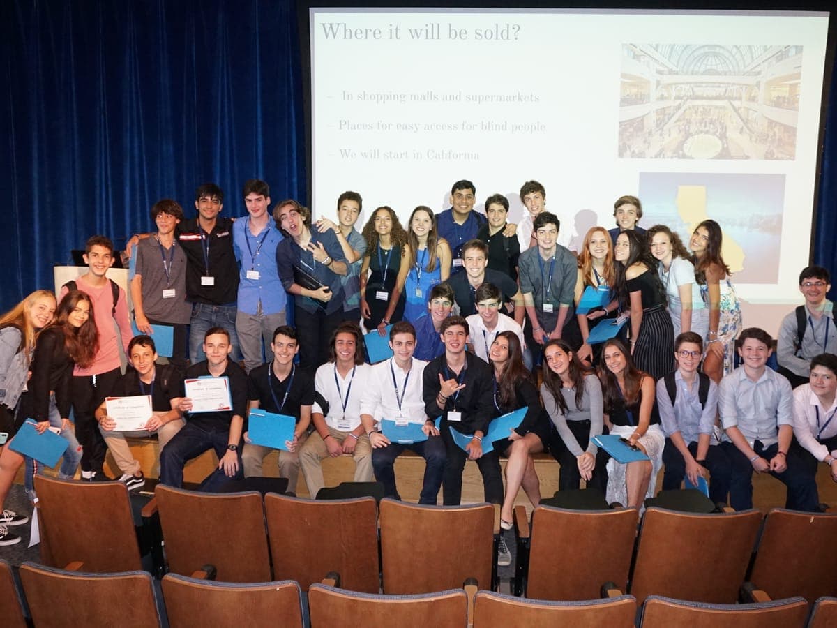 The cohort gathered on stage at the end of the Closing Ceremony, project folders in hand.