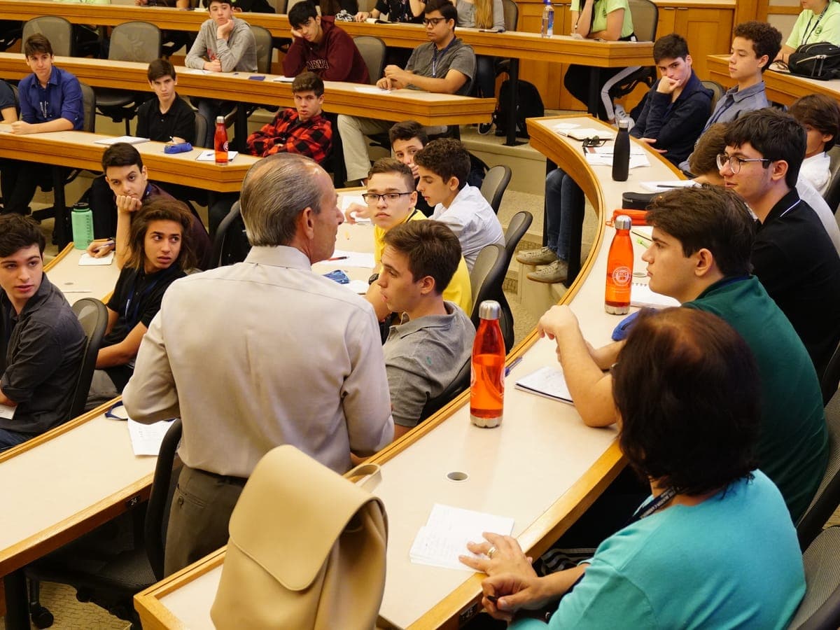 Case method session in a horseshoe shaped wooden lecture hall, the class following from three tiers of benches.