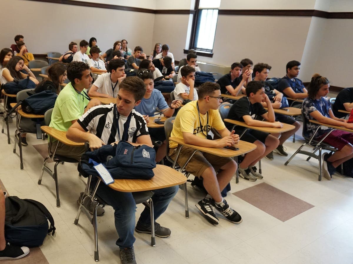 Participants in a university classroom, daylight coming through the windows.