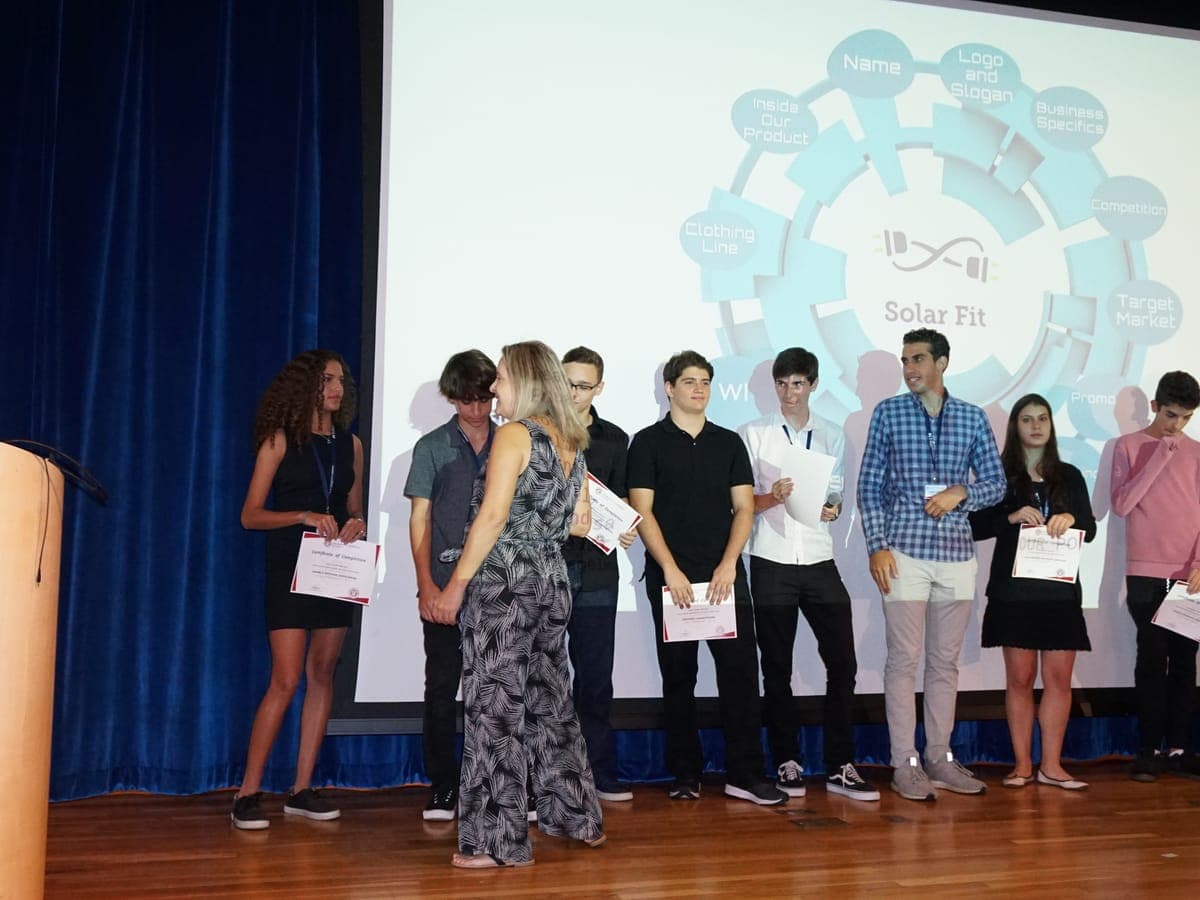 Certificates handed out on the Closing Ceremony stage, the team project projected behind.