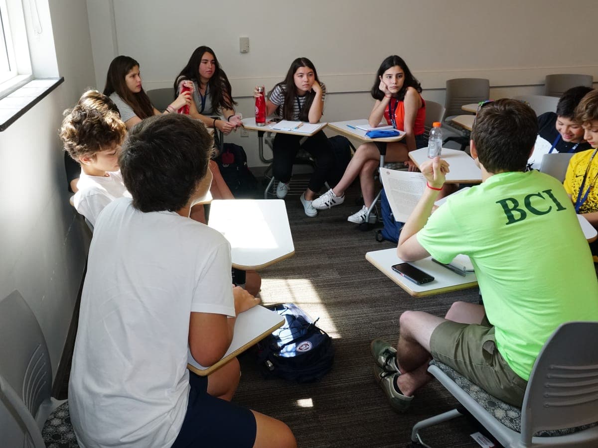 A team member sitting inside the circle with the printed handout, giving the group feedback in class.