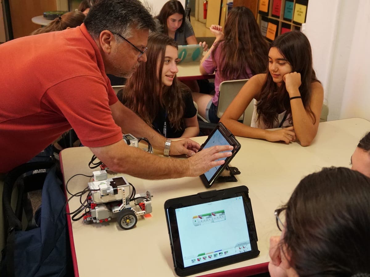 Educator guiding two participants at the tablet during the workshop.