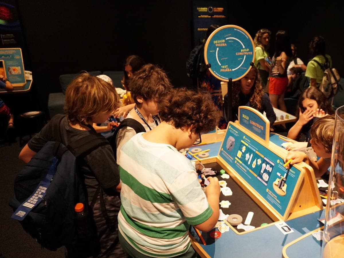 Participants assembling parts at the design, build and test benches of a science museum.