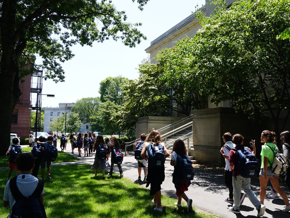 Group walking a campus path toward the historic buildings.